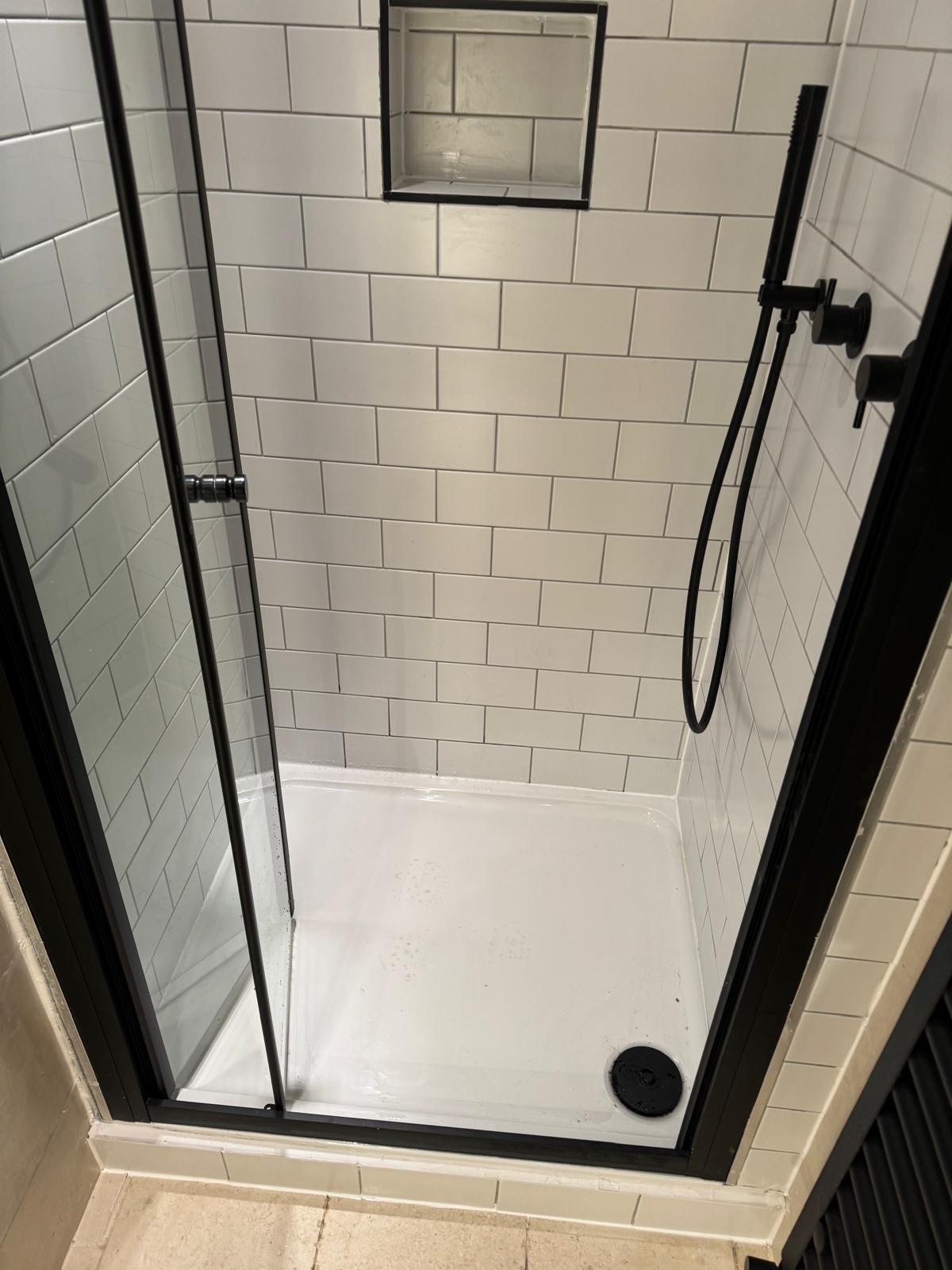 Walk-in shower enclosure with white metro tiles, black matte fittings and recessed niche shelf, bathroom installation W3