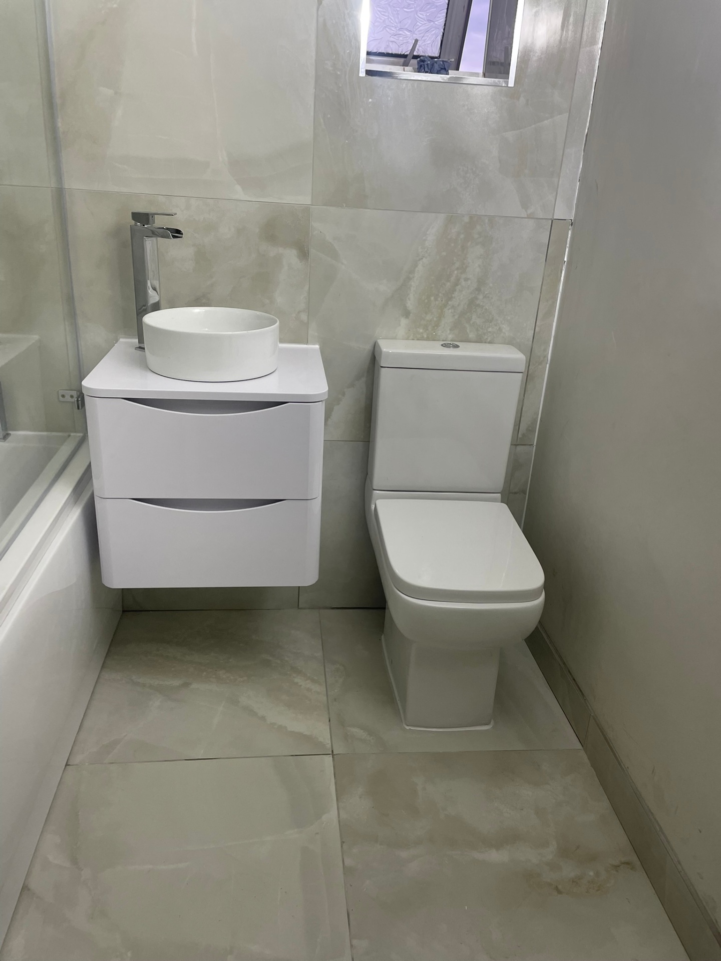 White floating vanity unit with round vessel basin next to a close-coupled toilet in an Ash Villa bathroom installation