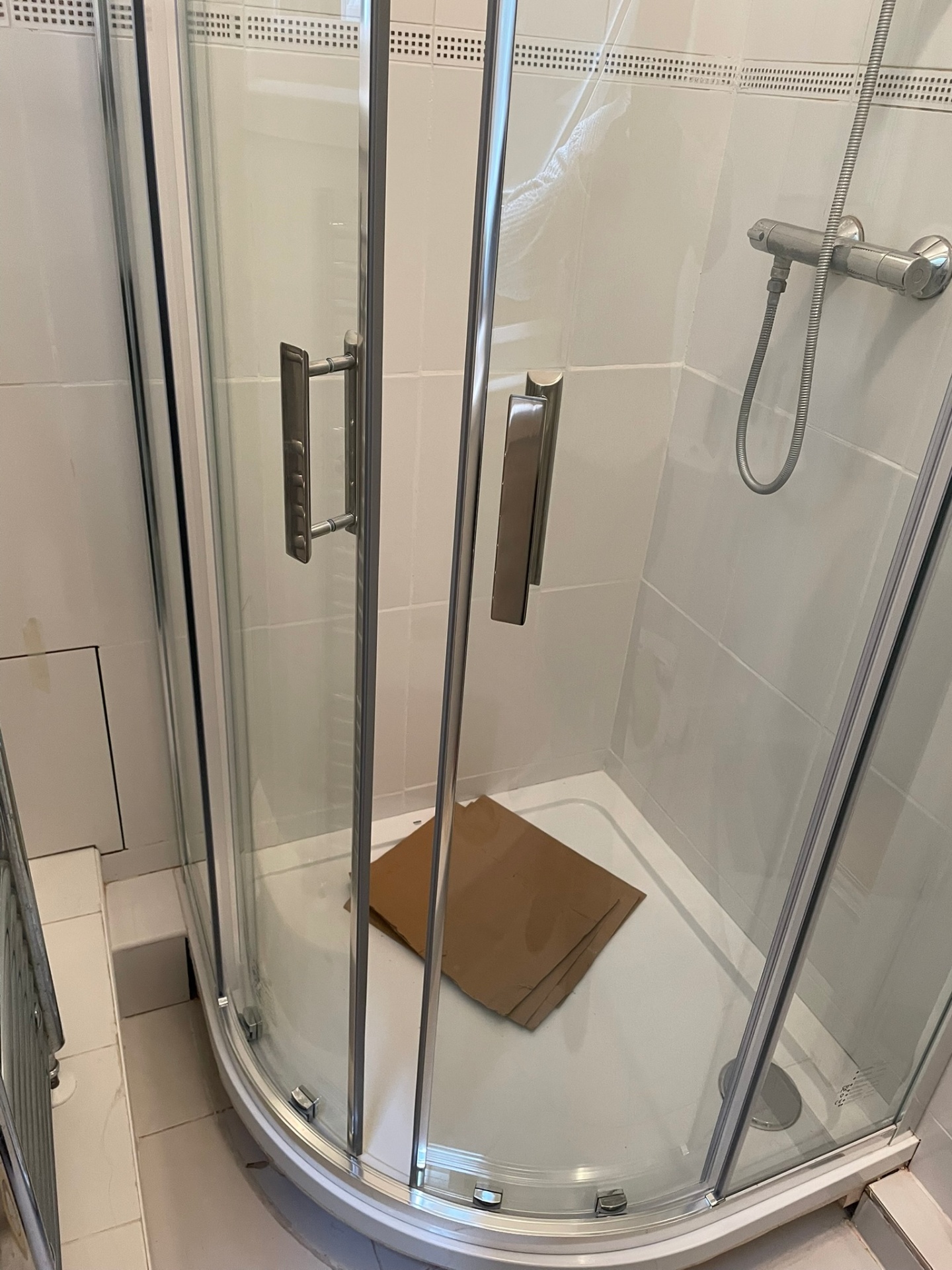 Glass quadrant shower enclosure with chrome handles and thermostatic bar valve fitted by Ash Villa in a West London bathroom
