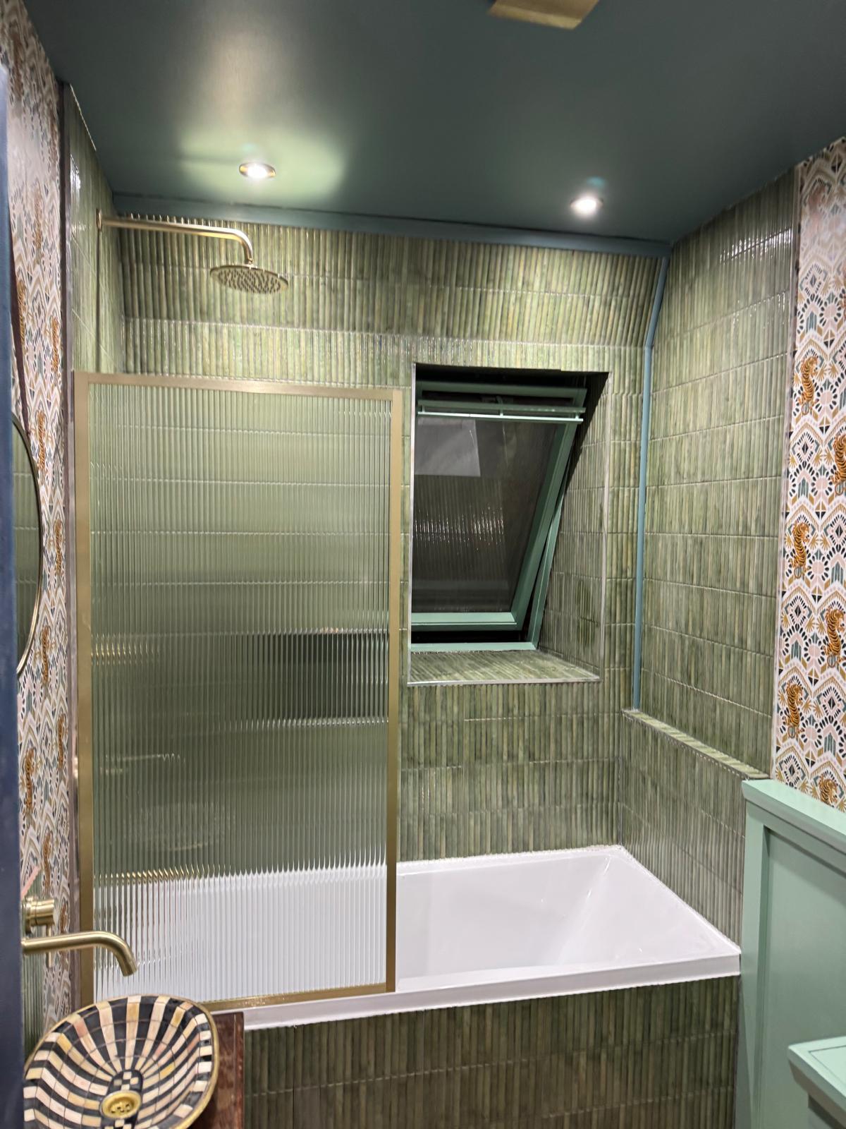 Finished bathroom with green vertical kit-kat tiles, gold shower and reeded glass bath screen by Ash Villa